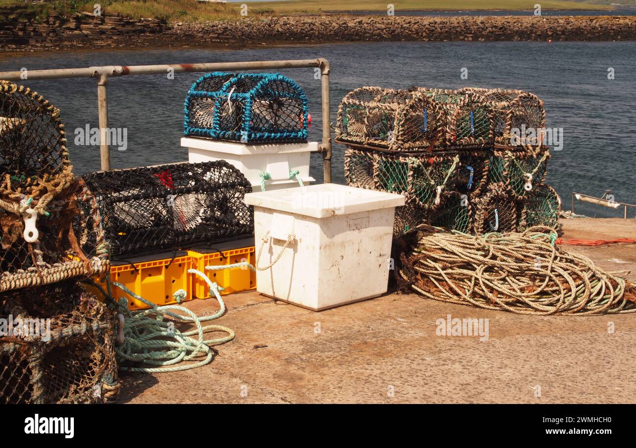 Nasses, boîtes de pêche et cordes empilées sur la jetée de Tingwall, avec la mer en arrière-plan, Orcades, Écosse Royaume-Uni Banque D'Images