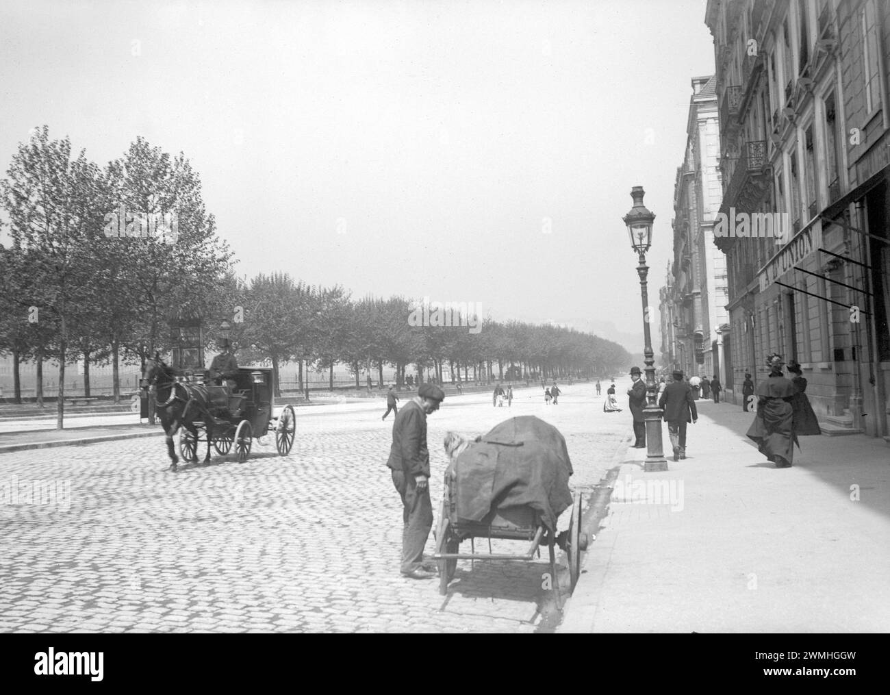 Quelqu'un avec un chapeau melon vendant des meubles dans une rue pavée de Paris. Début du XXe siècle. Ancienne photo restaurée. Banque D'Images