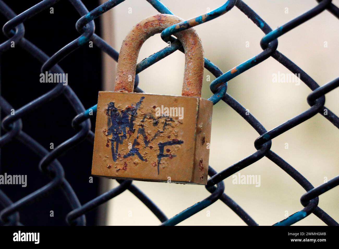 vieux cadenas colorés rouillés verrouillés sur un mur de filet Banque D'Images