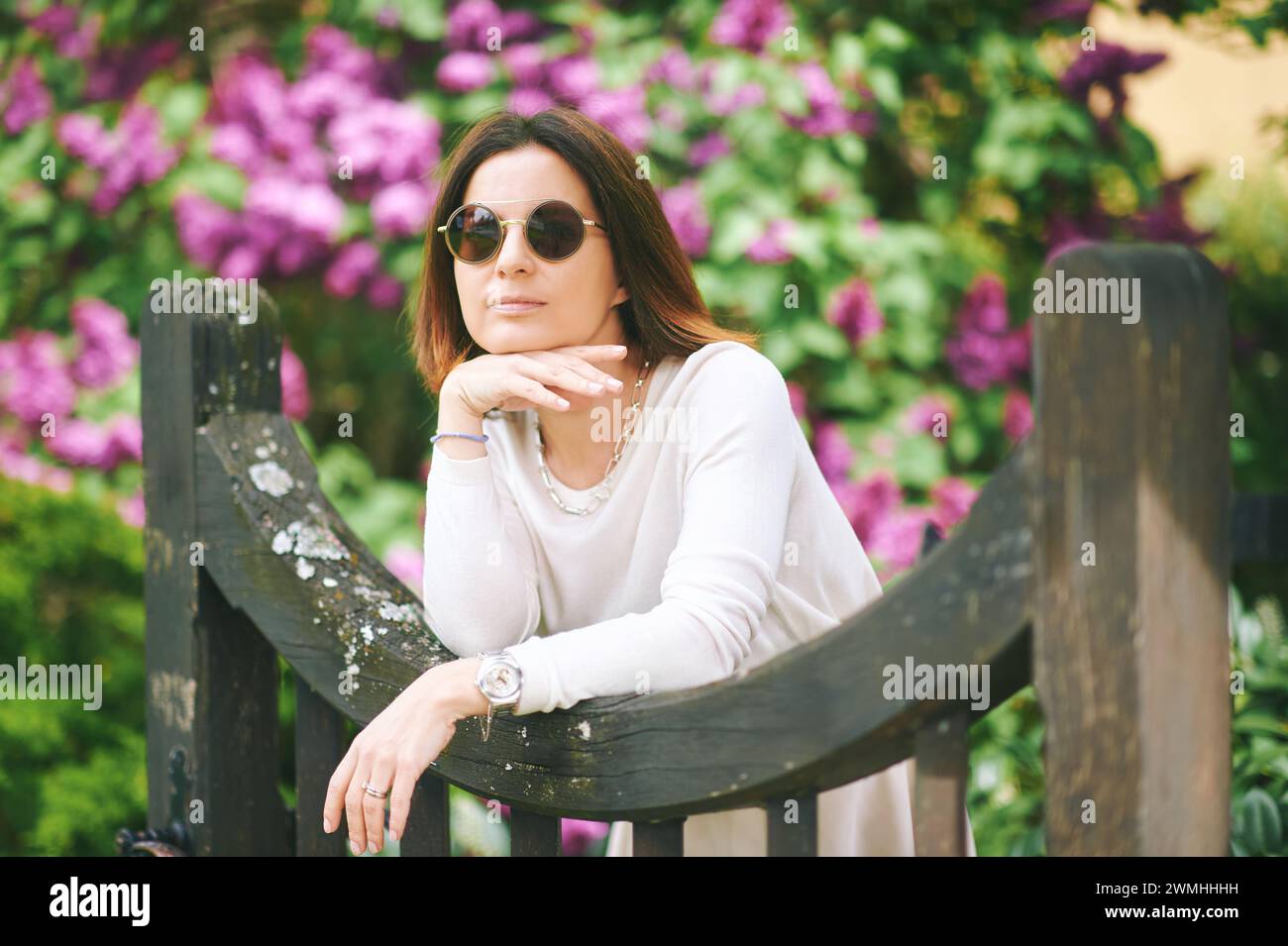 Portrait de printemps de jolie femme mature posant avec des fleurs de lilas sur fond Banque D'Images