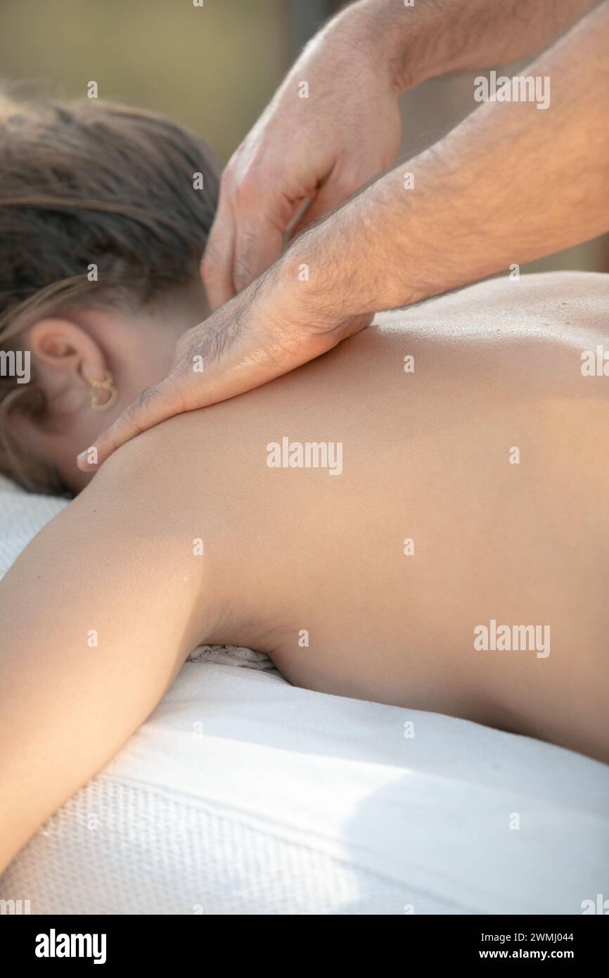 Massage professionnel du cou en tissu profond : mains concentrées appliquant une pression sur la zone cervicale du client féminin pour soulager la tension Banque D'Images