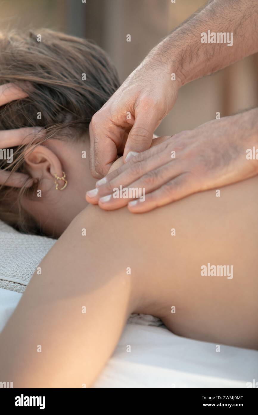 Massage professionnel du cou en tissu profond : mains concentrées appliquant une pression sur la zone cervicale du client féminin pour soulager la tension Banque D'Images