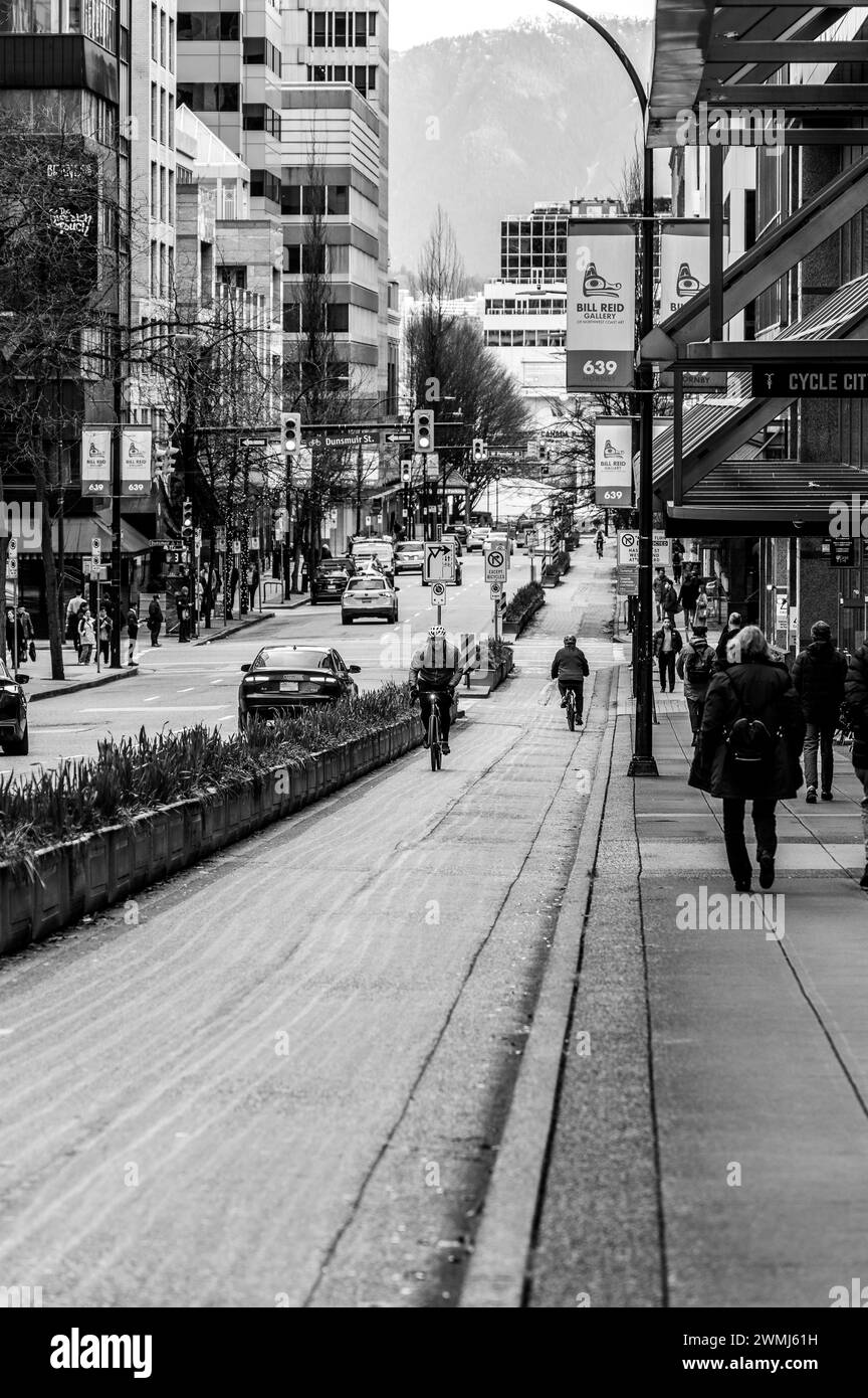 Vancouver, Canada - 15 février 2024 : une photo en noir et blanc d'un cycliste pédalant jusqu'à Hornby Street sur la piste cyclable. Banque D'Images