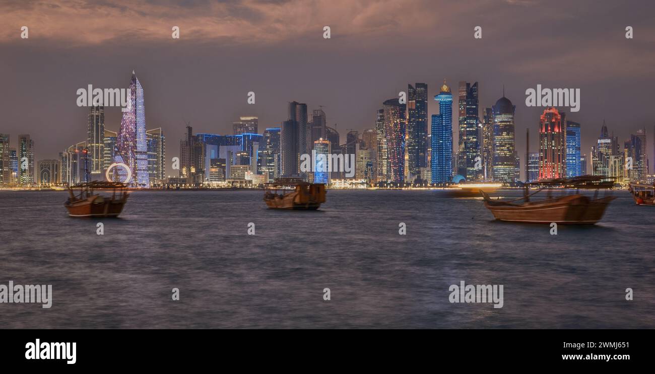 Doha, Qatar skyline de la promenade de la corniche la nuit avec des boudins et des bateaux dans le golfe arabe Banque D'Images
