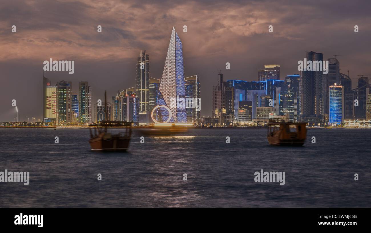Doha, Qatar skyline de la promenade de la corniche la nuit avec des boudins et des bateaux dans le golfe arabe Banque D'Images