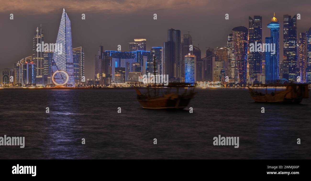 Doha, Qatar skyline de la promenade de la corniche la nuit avec des boudins et des bateaux dans le golfe arabe Banque D'Images