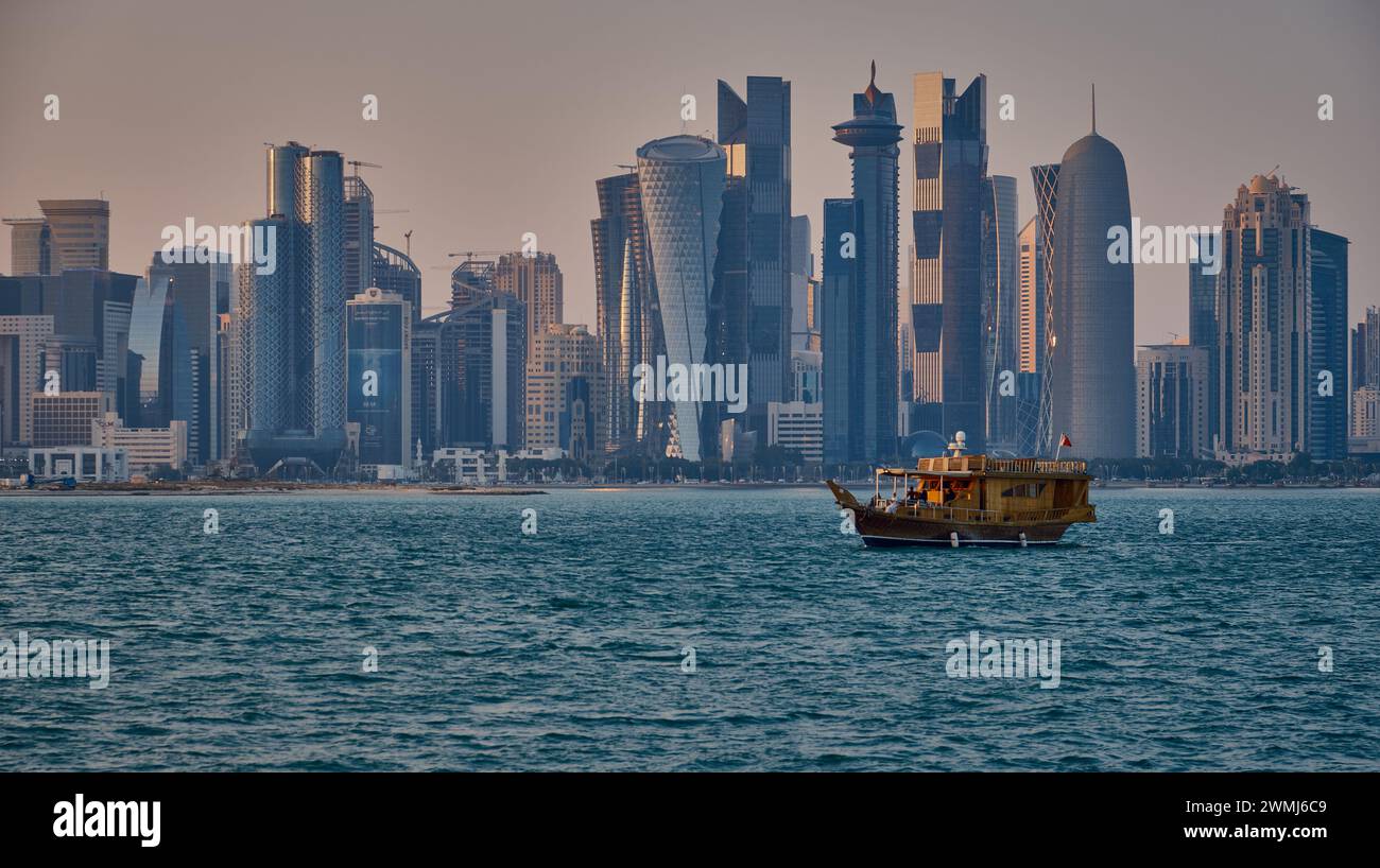 Doha, Qatar skyline au coucher du soleil avec des dhows et des bateaux dans le golfe arabe Banque D'Images