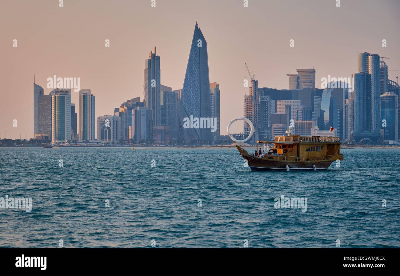 Doha, Qatar skyline de la rue corniche au coucher du soleil avec des boudins et des bateaux dans le golfe arabe Banque D'Images