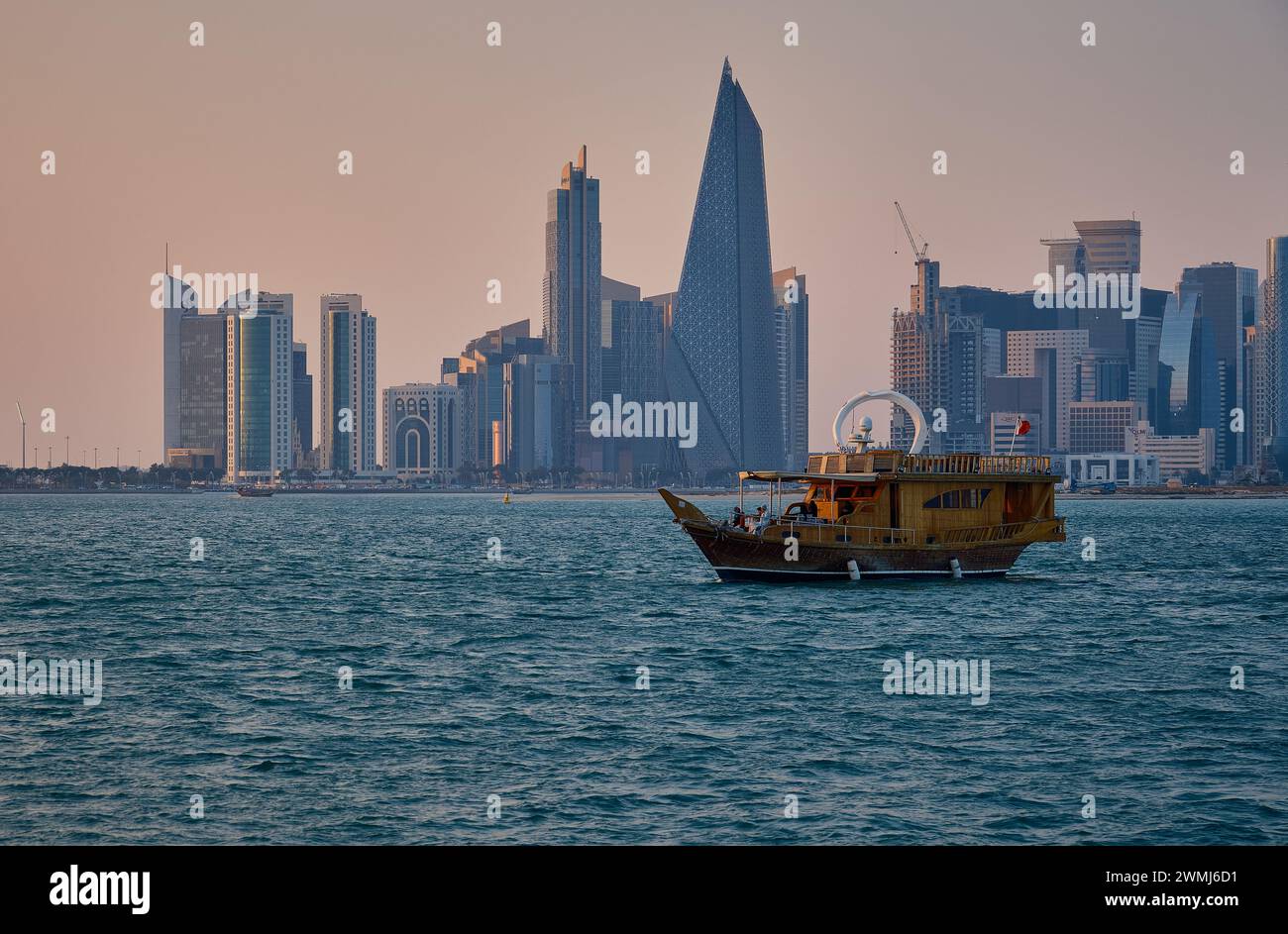 Doha, Qatar skyline de la rue corniche au coucher du soleil avec des boudins et des bateaux dans le golfe arabe Banque D'Images