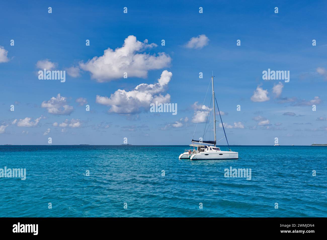 Bateau à voile blanc voyageant dans la mer bleue des Maldives sur une journée d'été ensoleillée au milieu de nulle part. Mer tropicale et voilier. Pas de voiles Banque D'Images