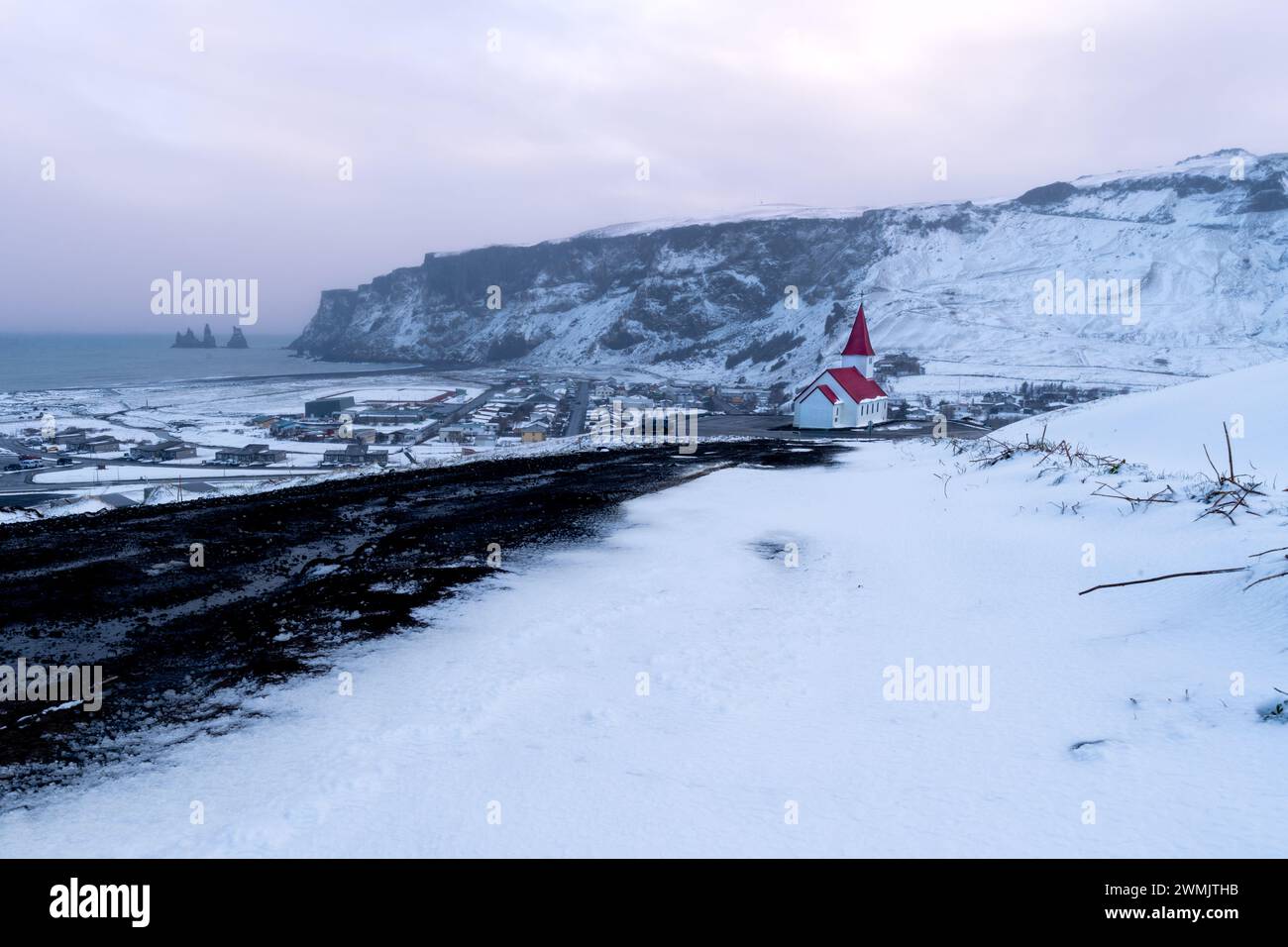 Vue sur la ville islandaise de Vik après une chute de neige au coucher du soleil Banque D'Images