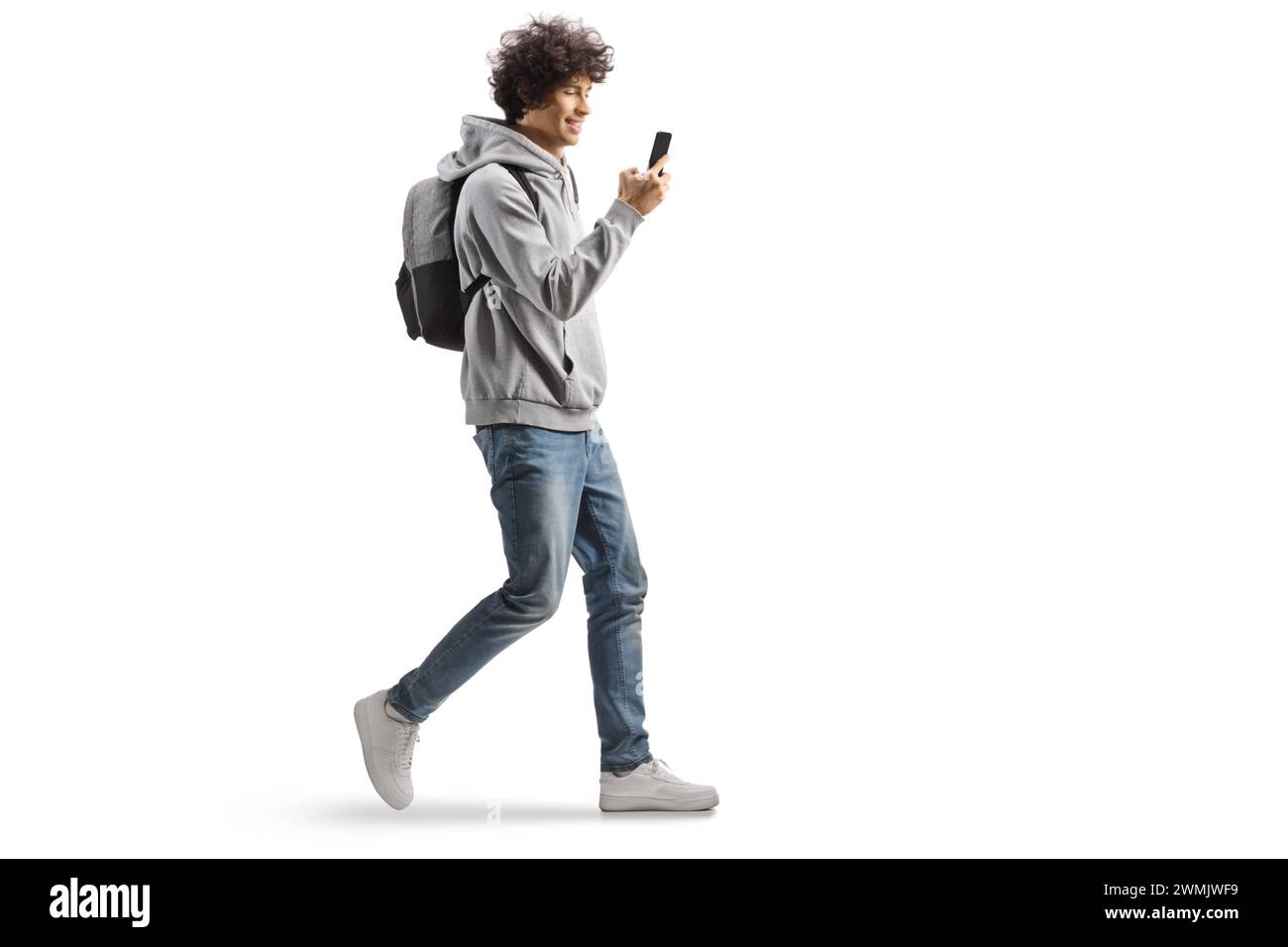 Étudiant portant un sac à dos et marchant avec un smartphone dans ses mains isolé sur fond blanc Banque D'Images