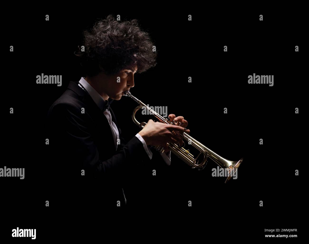Plan de profil d'un musicien jouant de la trompette isolé sur fond noir Banque D'Images