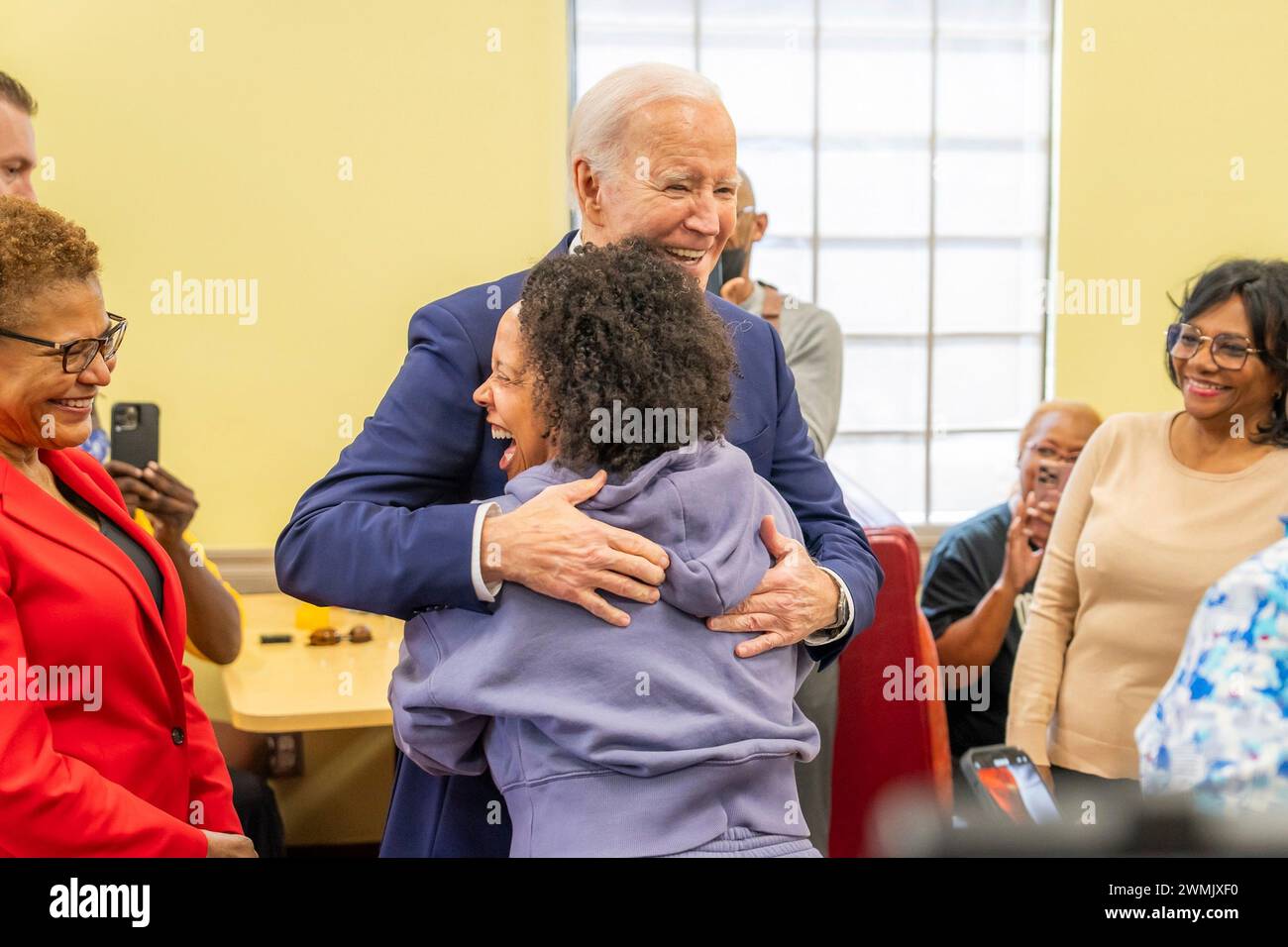 Culver City (États-Unis d'Amérique). 21 février 2024. Le président américain Joe Biden, au centre, est enlacé par un mécène alors que le maire Karen Bass, à gauche, regarde au CJ’s Café, le 21 février 2024 à Culver City, en Californie. Banque D'Images