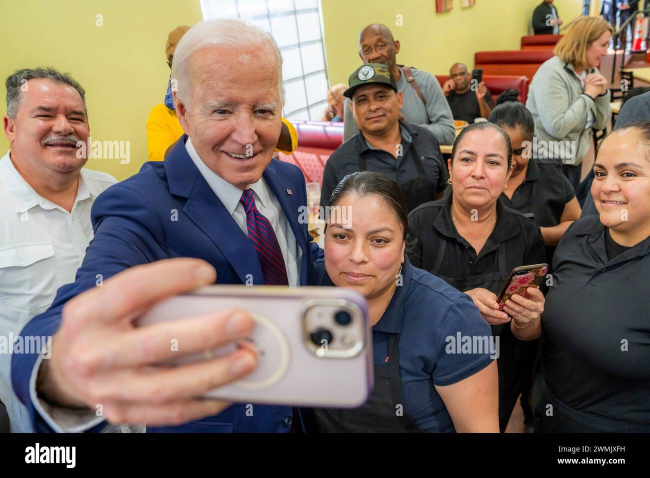 Culver City (États-Unis d'Amérique). 21 février 2024. Le président américain Joe Biden, à gauche, sourit pour un selfie avec les clients et le personnel au CJ’s Café, le 21 février 2024 à Culver City, en Californie. Banque D'Images