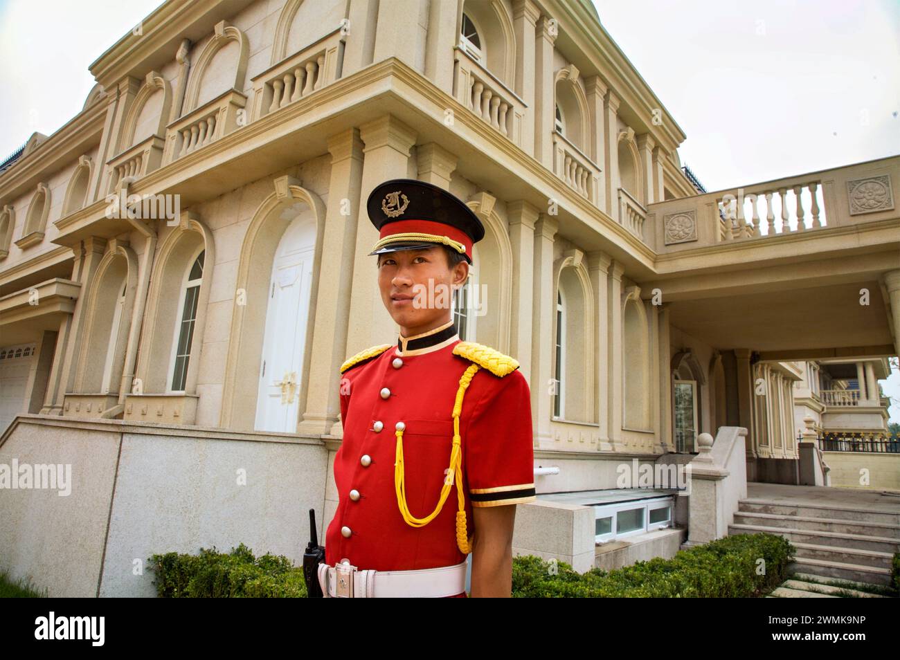 Un garde en uniforme rouge se tient à l'extérieur d'une grande villa dans le complexe Palais de Fortune à l'extérieur de Pékin ; République populaire de Chine Banque D'Images