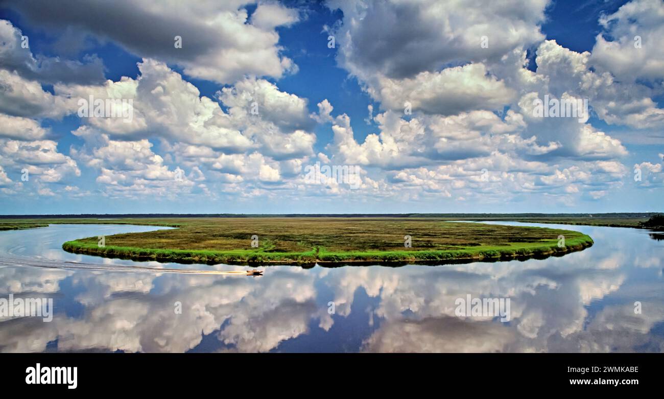 Bateau coupe à travers les reflets de nuages dans les eaux placides de la rivière Mary's dans le sud de la Géorgie. La Mary forme une division entre F... Banque D'Images