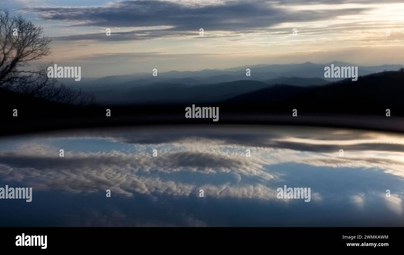 Reflet de nuages à la surface du vin dans un verre fixé avant une vue panoramique sur la montagne Banque D'Images