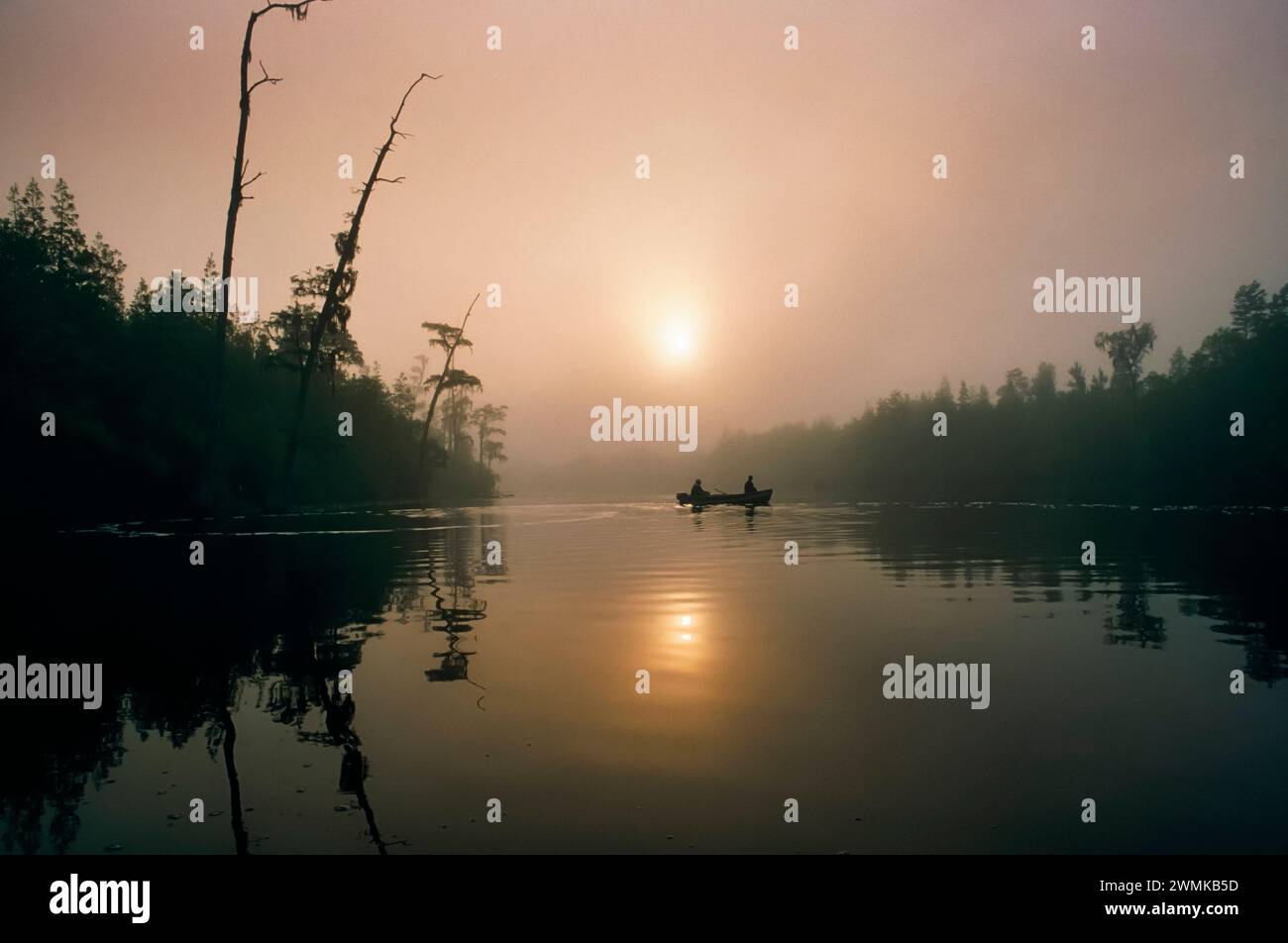 Un seul bateau de pêcheurs trolls à travers Billy's Lake dans le brouillard tôt le matin dans la réserve naturelle nationale d'Okefenokee. Entrée ouest du marais op... Banque D'Images