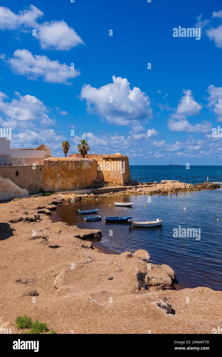 Petits bateaux amarrés le long de la rive de la vieille ville de Trapani par la mer avec la fortification Bastione Conca ; Trapani, Sicile, Italie Banque D'Images