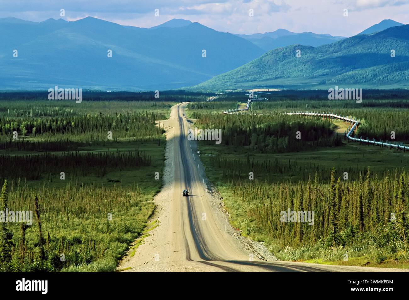 Un camion seul se déplace sur la Dalton Highway (également connue sous le nom de Haul Road) à travers la toundra verte avec une vue spectaculaire vers les montagnes, en cours d'exécution 414 ... Banque D'Images