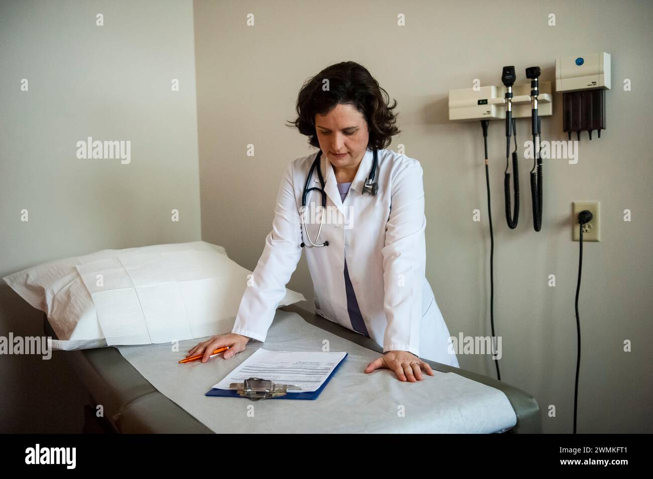 L'assistant du médecin étudie la paperasse dans une chambre vide ; Lincoln, Nebraska, Etats-Unis d'Amérique Banque D'Images
