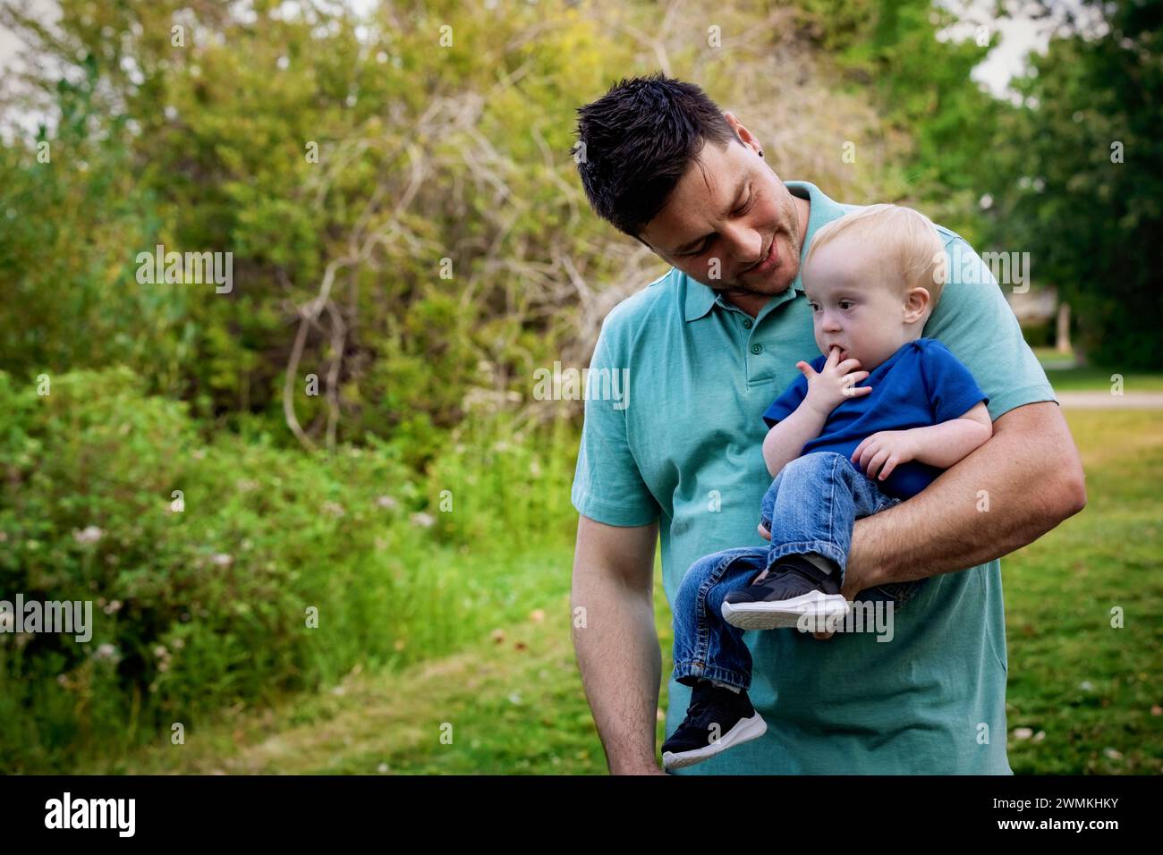 Père passant du temps de qualité à l'extérieur avec son jeune fils atteint du syndrome de Down, dans un parc municipal pendant un chaud après-midi d'automne ; Leduc, Alberta, Canada Banque D'Images