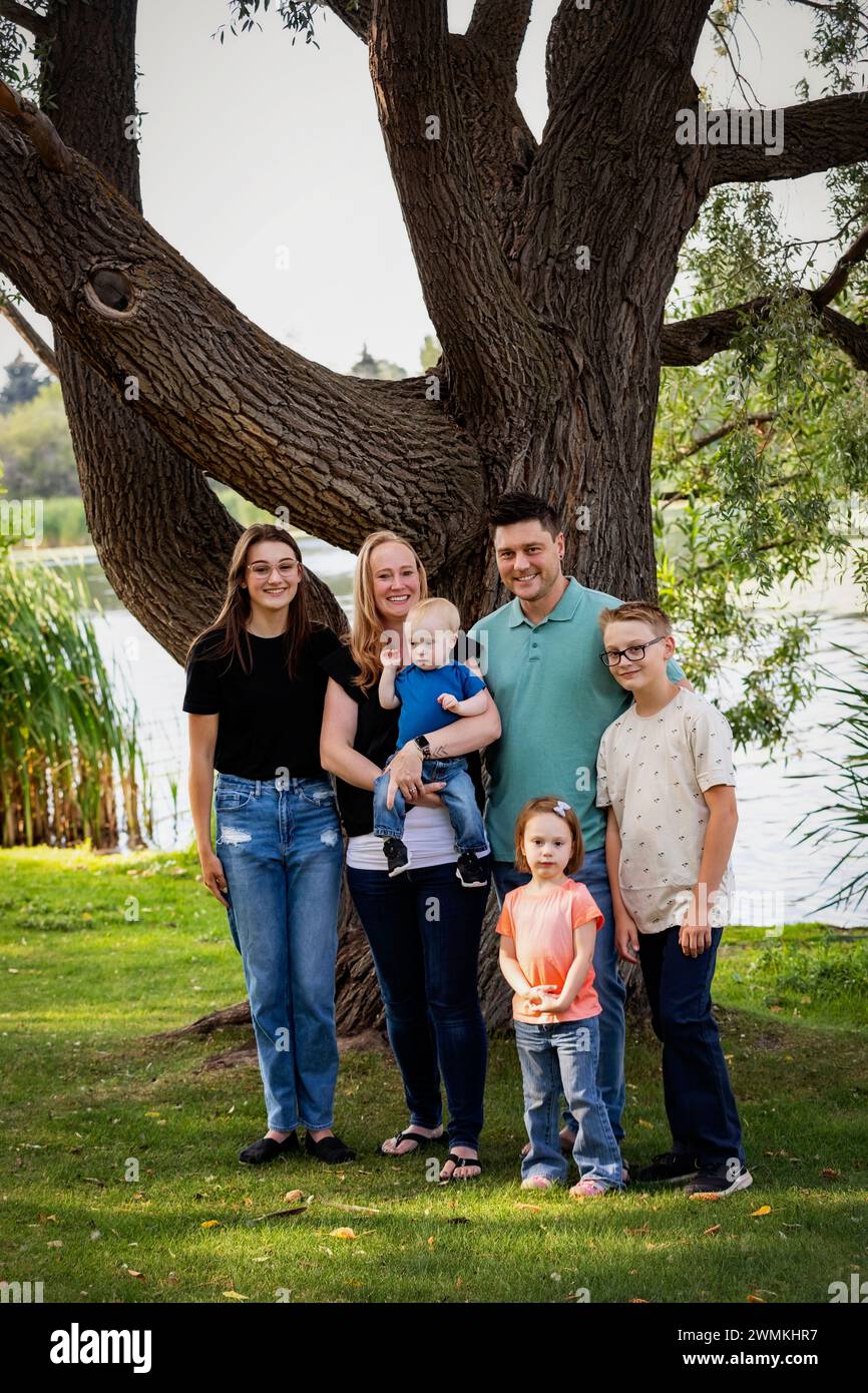 Portrait de famille en plein air dans un parc de la ville près d'un lac par un chaud après-midi d'automne et le plus jeune fils a le syndrome de Down ; Leduc, Alberta, Canada Banque D'Images