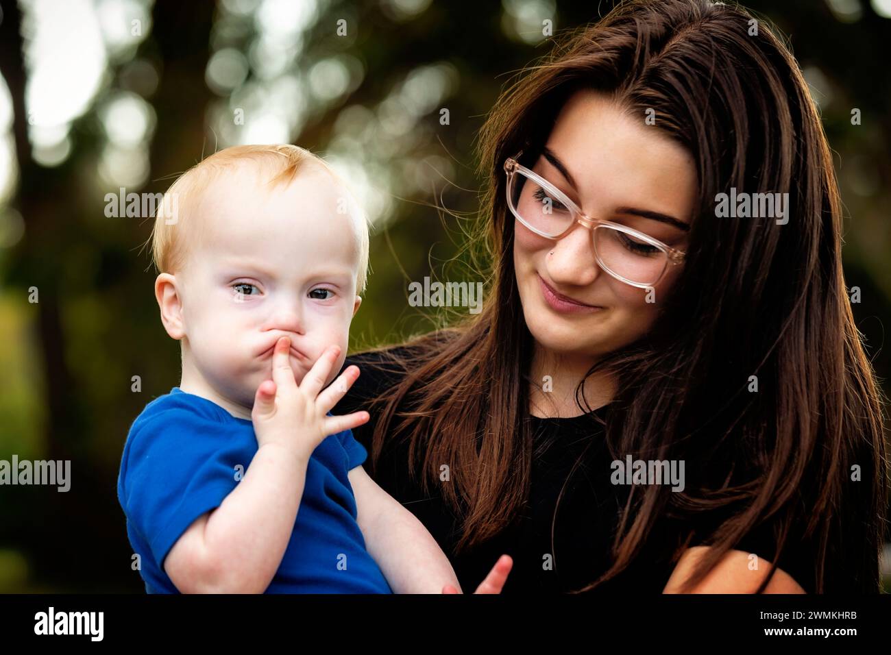 Portrait en plein air d'une sœur aînée passant du temps de qualité avec son jeune frère atteint du syndrome de Down, dans un parc de la ville lors d'un chaud après-midi d'automne Banque D'Images