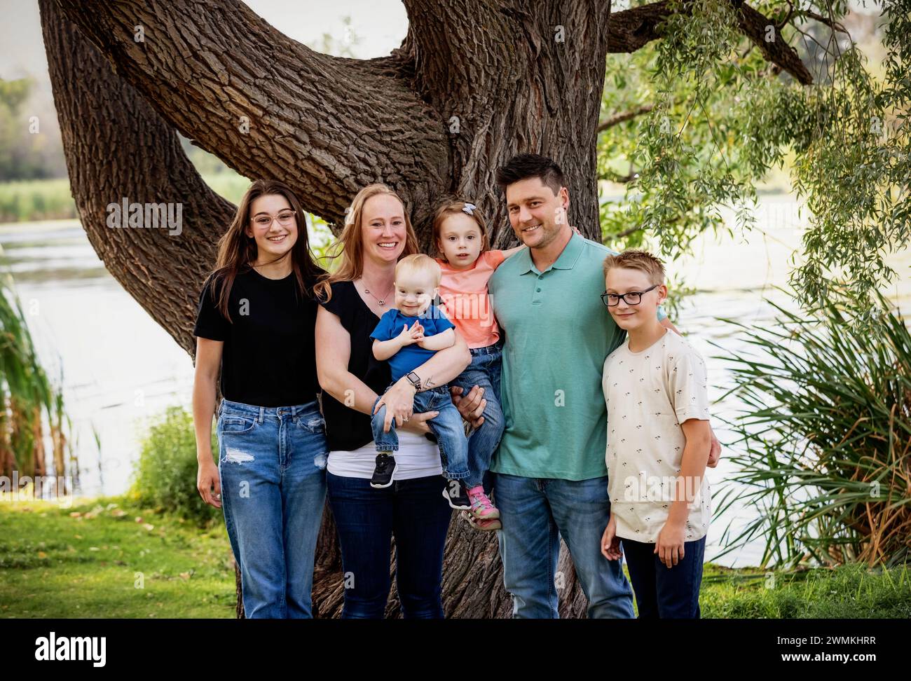 Portrait de famille en plein air dans un parc de la ville près d'un lac par un chaud après-midi d'automne et le plus jeune fils a le syndrome de Down ; Leduc, Alberta, Canada Banque D'Images