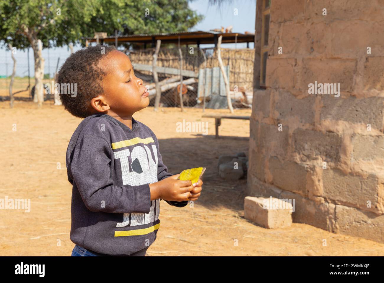 village enfant africain profitant du soleil dans la cour à côté de sa maison Banque D'Images