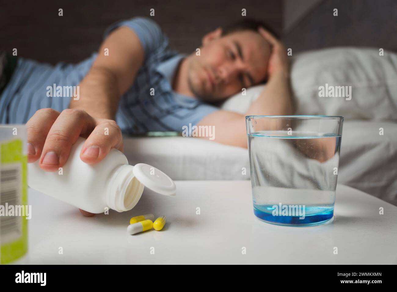 jeune homme prend des médicaments. automédication. guy est traité à la maison avec des pilules. Céphalées. insomnie, troubles du sommeil. Banque D'Images