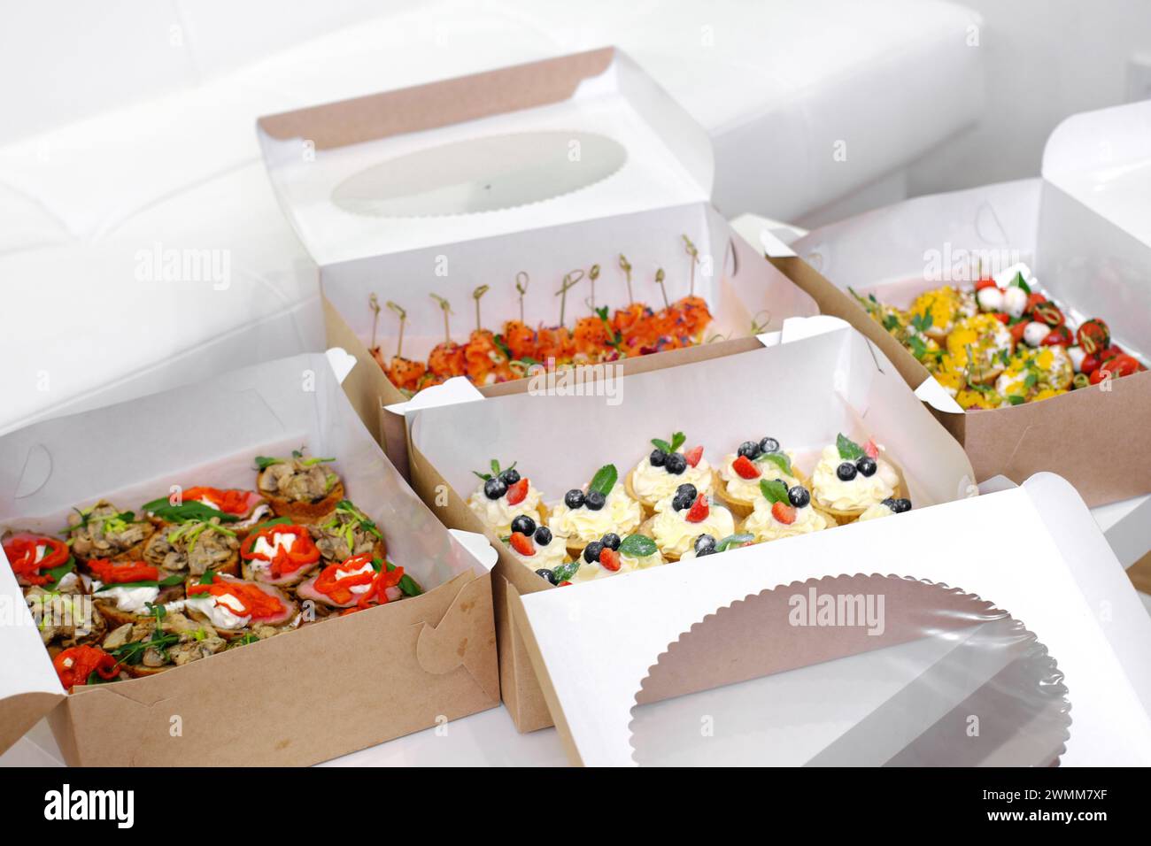 Boîtes de restauration remplies d'une sélection exquise de canapés et tartelettes, prêtes à être livrées pour un événement spécial. Banque D'Images
