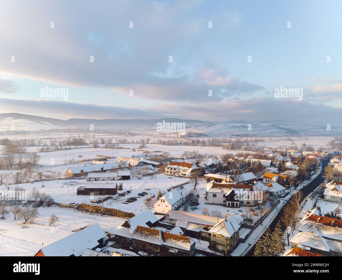 La neige recouvre les toits d'une ville déserte avec des maisons et des arbres Banque D'Images