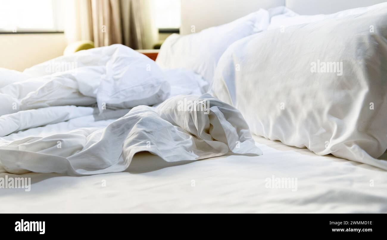 Oreillers blancs avec couverture sur le lit non fait, lit en désordre Banque D'Images
