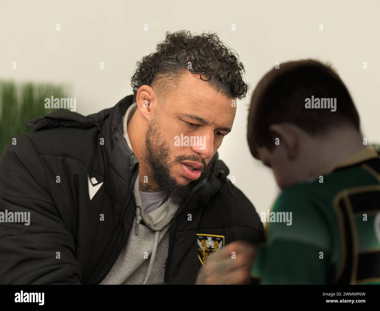 Courtney Lawes, joueuse internationale anglaise de rugby, signe le maillot d'un jeune fan du club de rugby des Northampton Saints, en Angleterre, lors d'une journée portes ouvertes, 2024. Banque D'Images