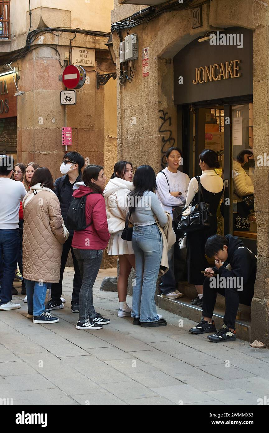 Barcelone, Espagne - 27 février 2024 : un groupe de personnes attend patiemment devant le magasin Joncake, capturant un moment urbain quotidien. Banque D'Images