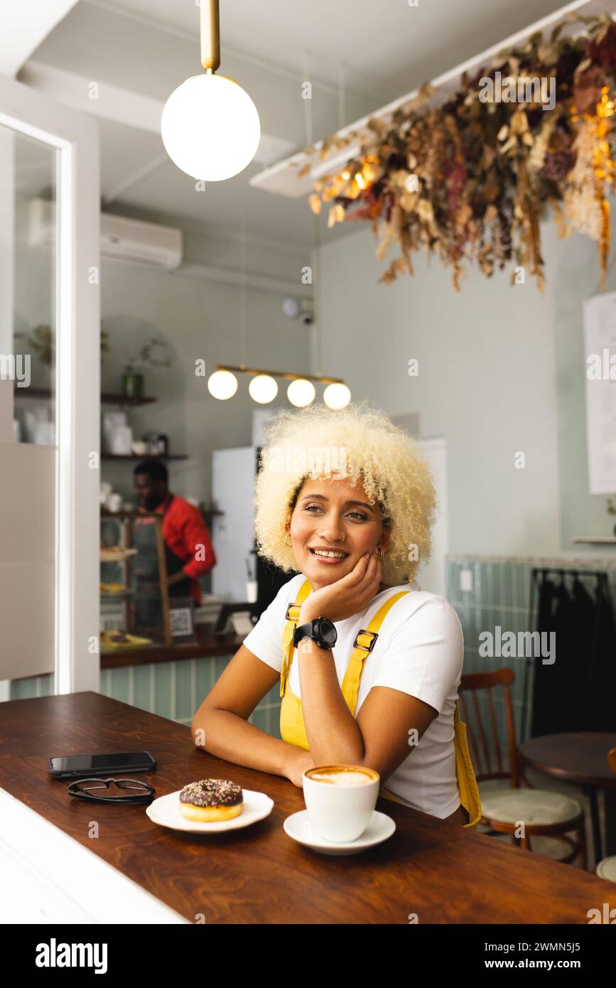 Jeune femme biraciale apprécie un café dans un café confortable, avec un espace de copie Banque D'Images
