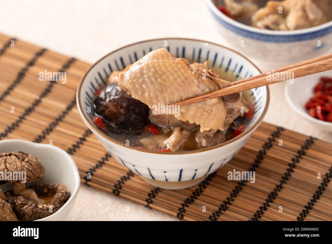 Délicieuse soupe de poulet aux champignons shiitake take taïwanais dans un bol sur fond de table blanc. Banque D'Images