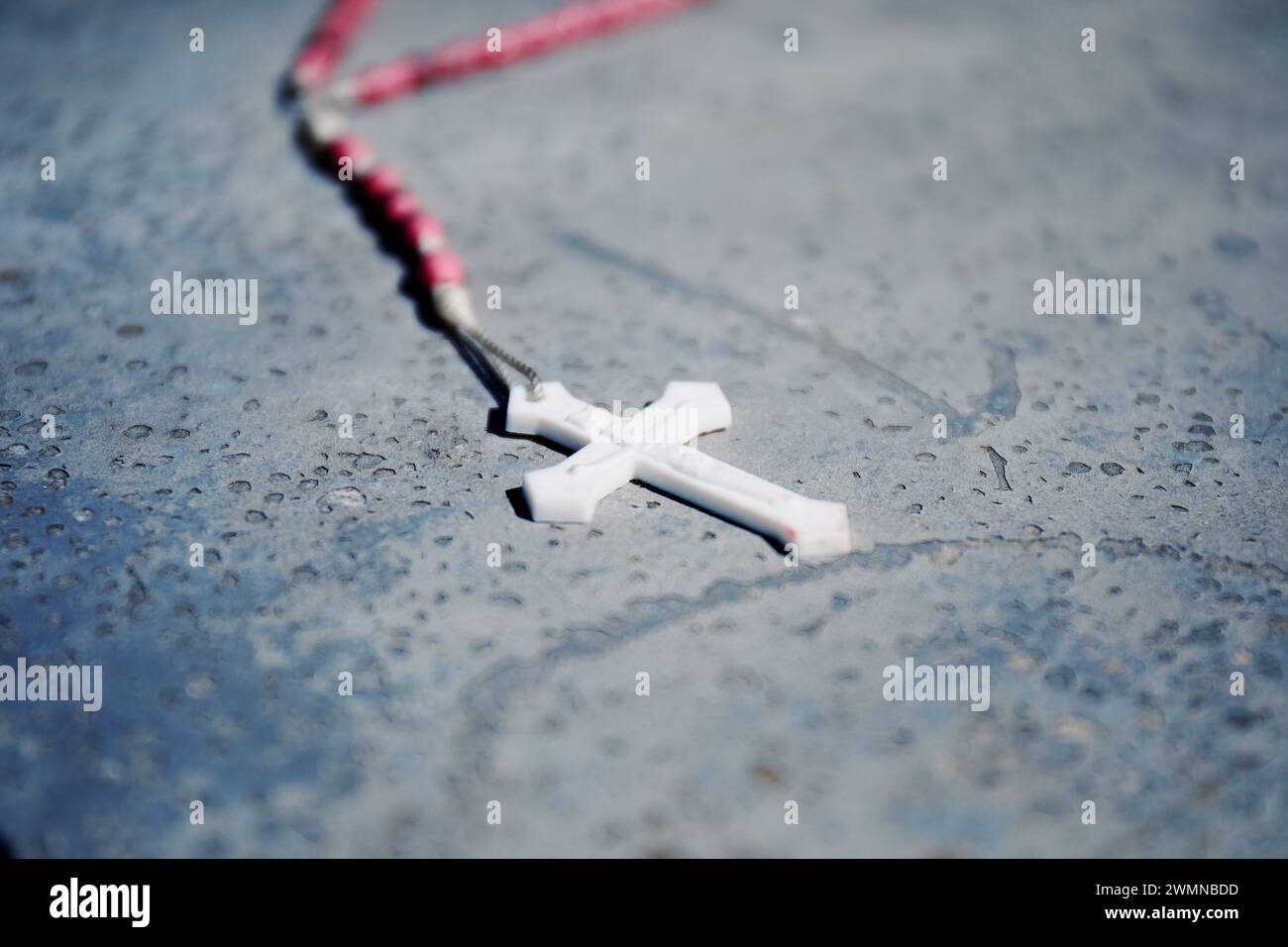 Crucifix en plastique blanc sur une sangle, mise au point partielle Banque D'Images