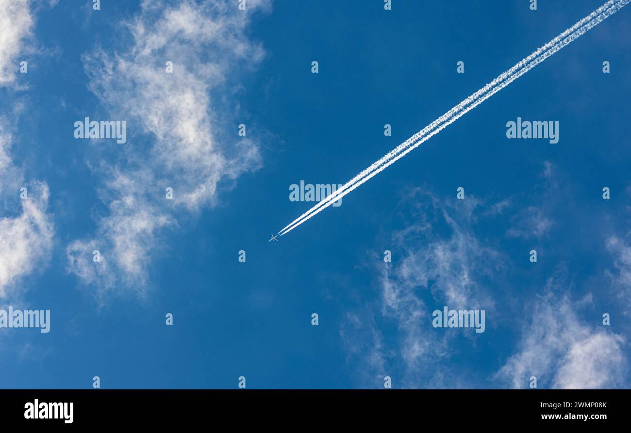 Ein Flugzeug zieht am leicht bewölkten Himmel einen Kondensstreifen hinter sich her. (Oberglatt, Schweiz, 12.05.2023) Banque D'Images