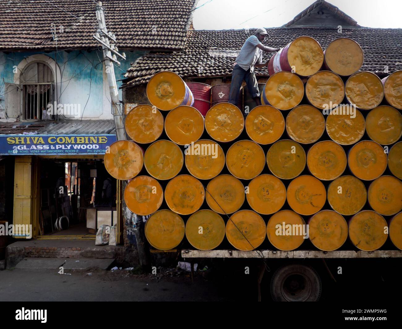 Inde, Kerala, Cochin : un homme enlève les poubelles jaunes de son camion Banque D'Images