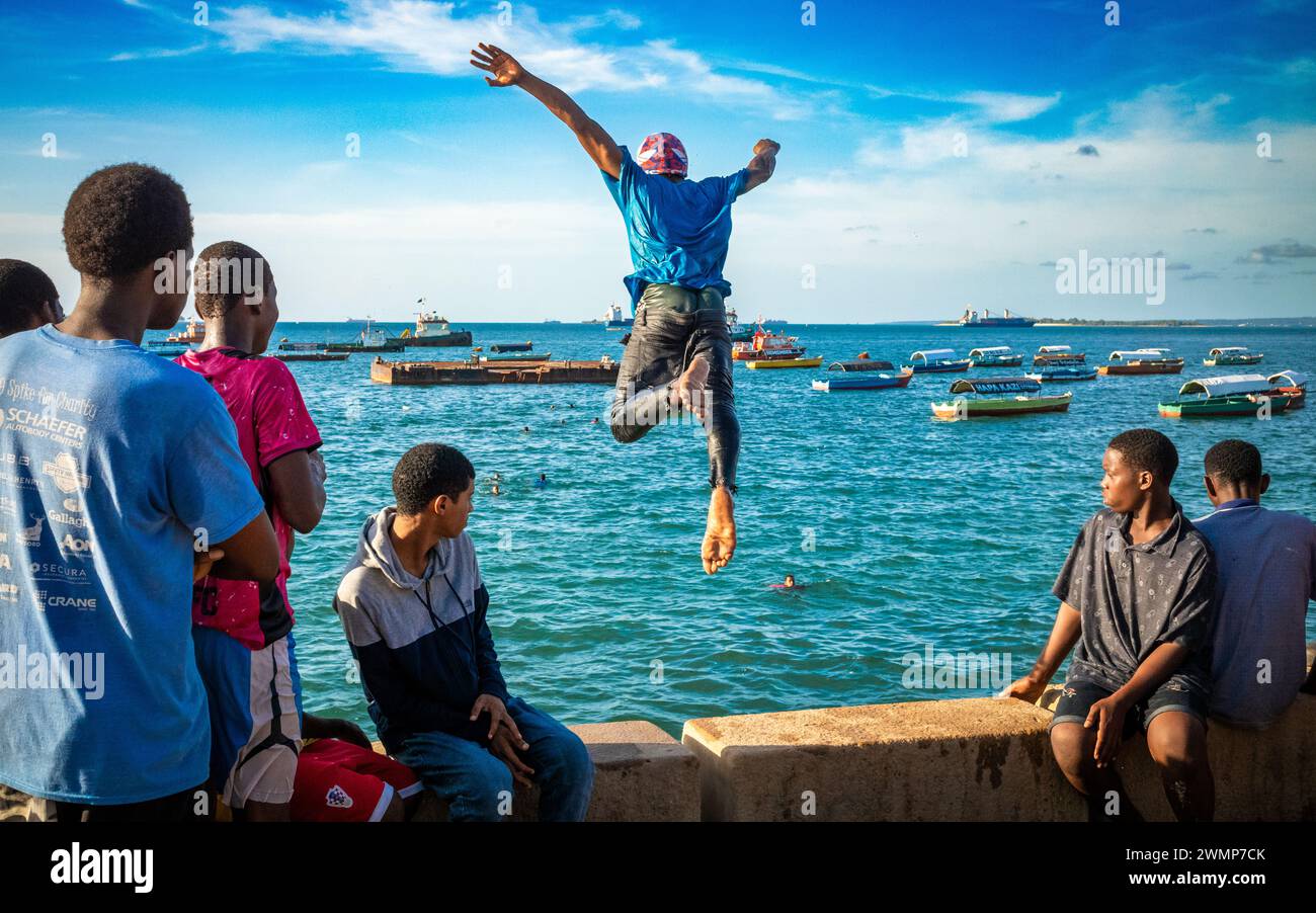 Des adolescents sautent et plongent hors de la digue à marée haute à Stone Town, Zanzibar, Tanzanie Banque D'Images