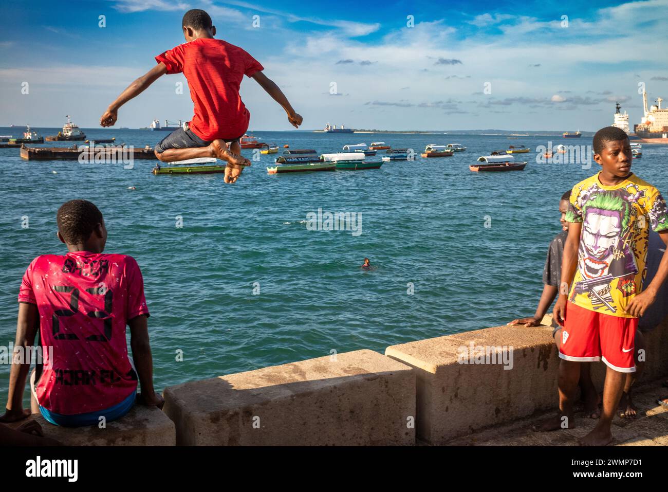 Des adolescents sautent et plongent hors de la digue à marée haute à Stone Town, Zanzibar, Tanzanie Banque D'Images