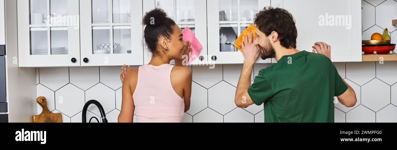 jolie petite amie multiraciale attrayante et petit ami dans des vêtements de maison confortables faisant des corvées dans la cuisine Banque D'Images