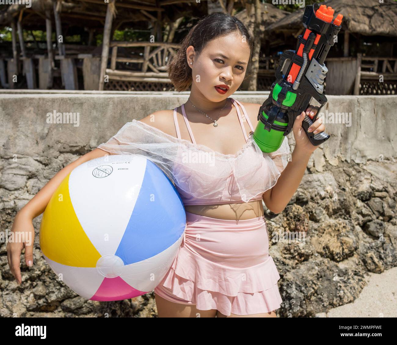 Une fille philippine avec un ballon de plage et un pistolet à eau Banque D'Images