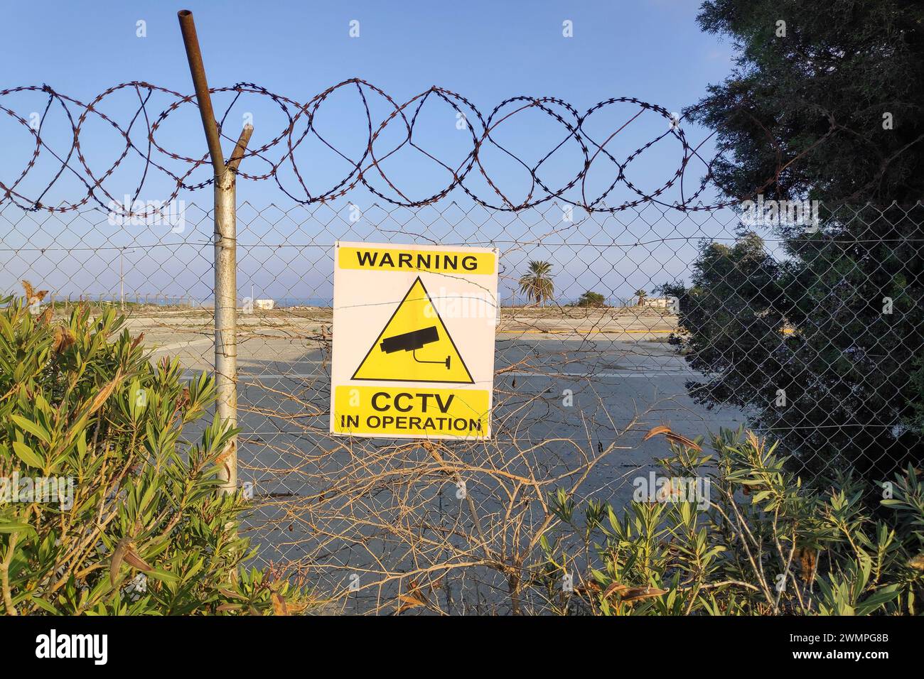 Panneau attaché à la clôture d'une friche industrielle au bord de la mer indiquant : avertissement, CCTV en fonctionnement. Banque D'Images