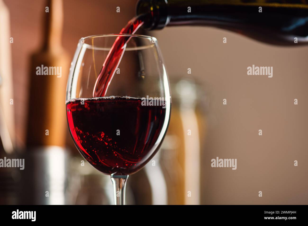 Vin rouge français se versant dans un verre en bulles avec un éclaboussure sur la table dans la cuisine, une photo studio de haute qualité Banque D'Images