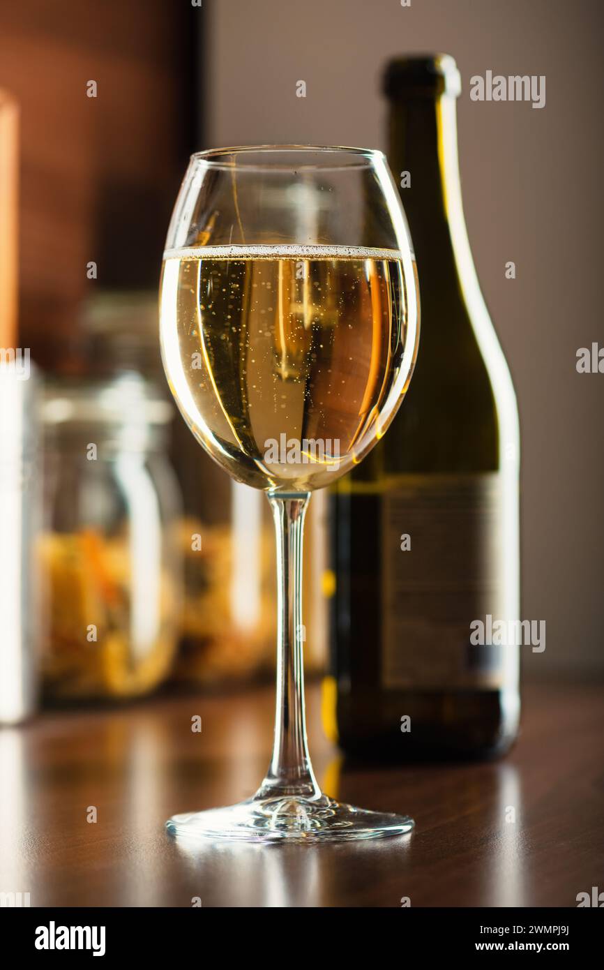 Vin blanc français en verre dans des bulles sur la table cuisine avec une bouteille de vin dans le gros plan en arrière-plan Banque D'Images