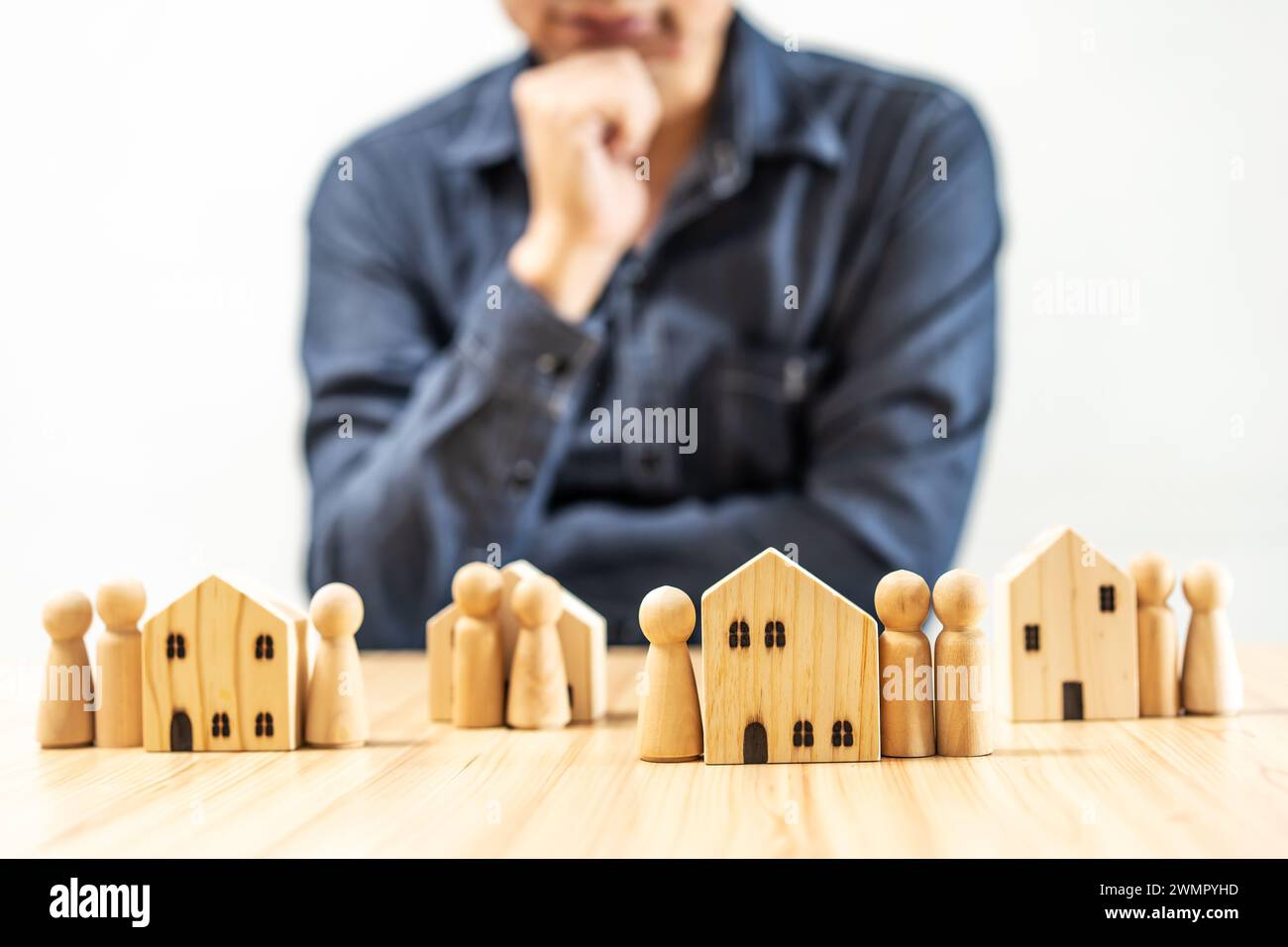 Homme debout près de maisons et de personnages en bois sur une table Banque D'Images